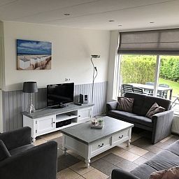 Lichte woonkamer met uitzicht op de tuin in Bungalow 23, een vakantiehuis in De Koog, Texel.