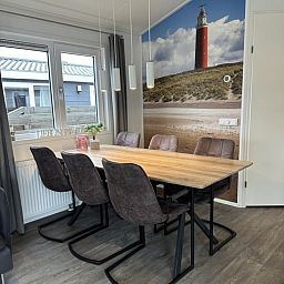 Gezellige eetkamer in Chaletpark Bregkoog, Chalet Bregkoog 232, De Koog, Texel met uitzicht op duinlandschap en comfortabele stoelen.