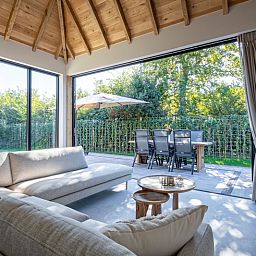 Ruime woonkamer met openslaande deuren naar tuin van Villa Flo in De Koog, Texel.