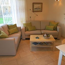 Gezellige woonkamer van Bungalow 't Luwe Land 49 in De Koog Texel, met comfortabele banken en uitzicht op de natuur van de Waddeneilanden.