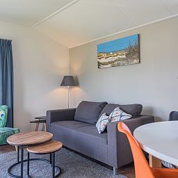 Gemuetliches Wohnzimmer des Chalets Bregkoog 227 in De Koog, Texel, mit bequemen Sitzgelegenheiten und moderner Einrichtung.