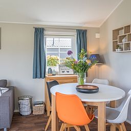 Essecke im Chalet Bregkoog 227, Chaletpark Bregkoog, De Koog, Texel mit bunten Stuehlen und einem stilvollen Tisch.