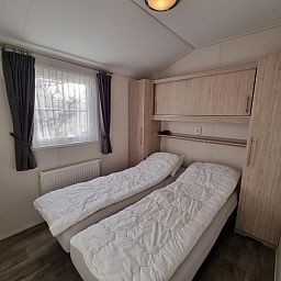 Knusse slaapkamer in Chaletpark Bregkoog - Chalet Bregkoog 235, De Koog, Texel met twee eenpersoonsbedden en kastruimte.
