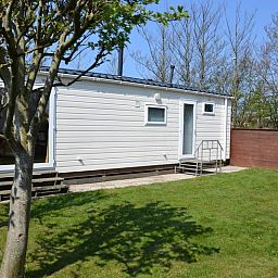 Camping Coogherveld - Chalet Jori in De Koog, Texel, bietet einen ruhigen Aussenbereich mit gruenem Garten und schoener Terrasse.