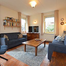 Ruime zithoek in Vakantiehuis 7K, De Koog, Texel met boekenplank en uitzicht op de tuin.