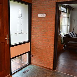 Ingang van Orchismient 28 in De Koog Texel met bakstenen muren en glazen deur.