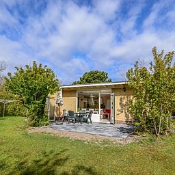 Terrasse des Bungalows 51 in 't Luwe Land, De Koog, Texel, mit Gartenmoebeln und gruener Umgebung.