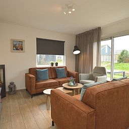 Gemuetliches Wohnzimmer des Ferienhauses Stappeland 215 in De Koog, Texel, mit bequemer Sitzecke und Gartenblick.