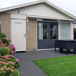 Terras van vakantiehuis De Anemoon in De Koog, Texel. Ruime buitenruimte met tuinmeubilair en bloeiende planten.
