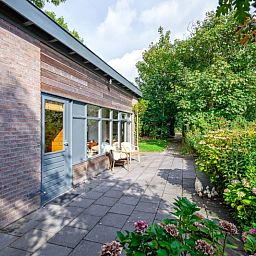 Veranda van De Zonneweelde vakantiehuis in De Koog, Texel met groene omgeving.
