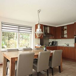 Gezellige eetkamer in 6 Persoons luxe villa met sauna in De Koog, Texel, met houten tafel en keuken.