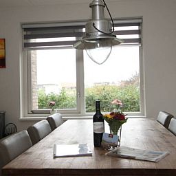 Eettafel met wijn en bloemen in 6 Persoons luxe villa met sauna in De Koog, Texel, met tuinzicht.