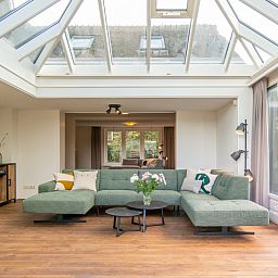 Bright living room of Kamerstraat 66 vacation home in De Koog Texel with glass roof and comfortable seating area.