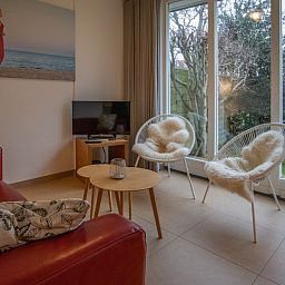 Knusse zithoek in vakantiehuis Zusje van 17, De Koog, Texel met comfortabele stoelen en tuinzicht.