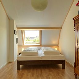 Lichte slaapkamer in vakantiehuis Zusje van 17, De Koog, Texel met houten vloer en groot raam.