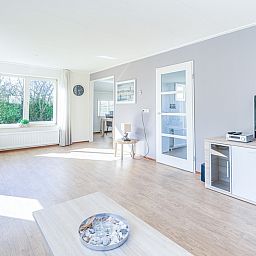 Spacious living room in Holiday Home Honeysuckle 95, De Koog, Texel with lots of natural light and views of the garden.