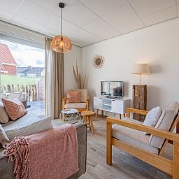 Lichte woonkamer van De Duinroos vakantiehuis in De Koog, Texel met toegang tot terras.