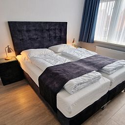 Stijlvolle slaapkamer in Vakantiehuis Duinzee Texel, De Koog, met groot raam en natuurlijke lichtinval.