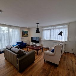Helles und geraeumiges Wohnzimmer im Bungalow Epelaan 13, De Koog, Texel. Ferienhaus mit stilvoller Einrichtung und grossen Fenstern.