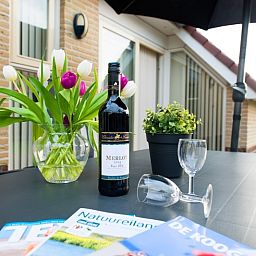 Geniet van een glas wijn op het terras van Villa 9, vakantiehuis in De Koog Texel, omgeven door natuur.