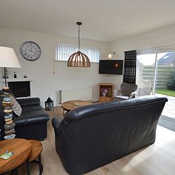 Gezellige woonkamer in Vakantiehuis Stappeland 205, De Koog, Texel met comfortabele banken en tuinzicht.