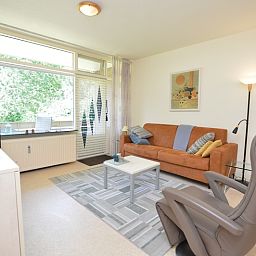 Lichte woonruimte in Appartement Kerckeland 64, De Koog, Texel met grote ramen en uitzicht op groen.