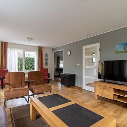 Lichte woonkamer van Vakantiehuis Kamperfoelie 43 met sauna, De Koog, Texel, met grote ramen en knusse zithoek.