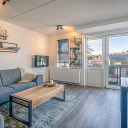 Modernes Wohnzimmer des Appartements Zeedistel 20, De Koog, Texel mit Zugang zum Balkon und Blick auf die Natur.