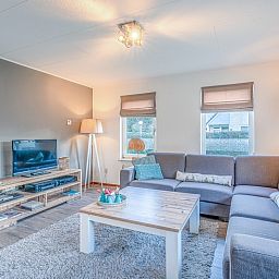 Geraeumiges Wohnzimmer im Ferienhaus Kamperfoelie 87, De Koog, Texel mit stilvoller Einrichtung und Fernseher.