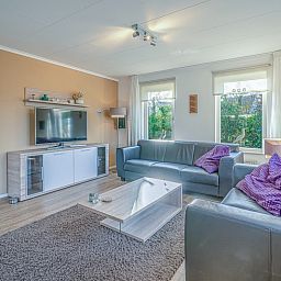 Stilvolle Sitzecke im Ferienhaus Kamperfoelie 59, De Koog, Texel mit geraeumigen Sofas und einem Flachbildfernseher.