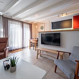 Lichte woonkamer in 32b Pollux, vakantiehuis in De Koog, Texel met zithoek en grote ramen voor natuurlijk licht.