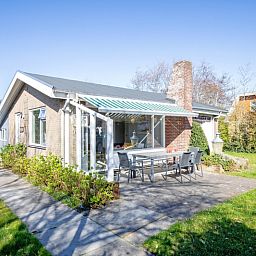 Terras met zonnescherm bij De Schutstal vakantiehuis in De Koog, Texel