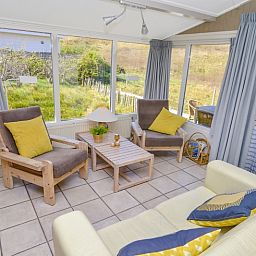 Gemuetliches Wohnzimmer des Ferienhauses Achter de Brem, De Koog, Texel mit Blick auf die Natur.