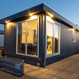 Buitenkant van Chalet Bregkoog 261 bij Chaletpark Bregkoog, De Koog, Texel, sfeervol verlicht in de avond.