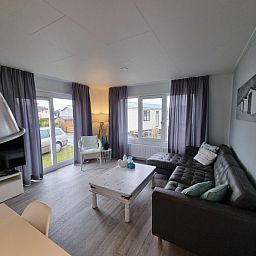 Woonkamer van Chalet Bregkoog 82, De Koog, Texel met comfortabele zithoek en grote ramen.