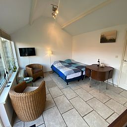 Binnenruimte van Studio Ooster - Brink 28 in De Koog, Texel, met zithoek en slaapgedeelte.
