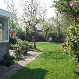 Groene tuin met terras bij Plevierstraat 21, De Koog, Texel, vakantiehuis voor natuurgenieters op de Waddeneilanden.
