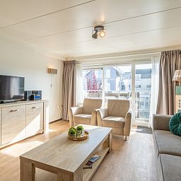 Ruime woonkamer met TV en balkon in Appartement Anna 218, De Koog, Texel, ideaal voor ontspanning.