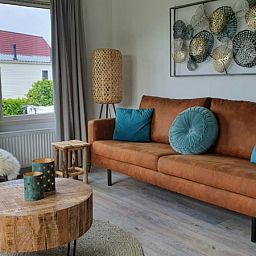Gezellige woonkamer van Chalet Bregkoog 154 in De Koog, Texel met comfortabele bank.