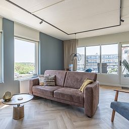 Sunny living room of Apartment Juliana 120 Eilandzicht, De Koog, Texel with comfortable sofa and view of Texel.