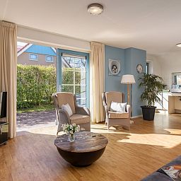 Bright living room of bungalow T6AM in De Koog, Texel, with comfortable interior and garden view, ideal for relaxation.
