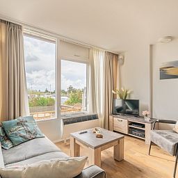 Lichte leefruimte van Appartement Juliana 076 Eilandzicht in De Koog, Texel met comfortabele zithoek en buitenzicht.