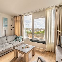 Stijlvolle binnenruimte van Appartement Juliana 076 Eilandzicht, De Koog, Texel met uitzicht op groene omgeving.