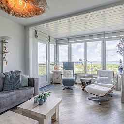 Gezellige woonkamer van Appartement Juliana 106 Zeezicht in De Koog, Texel met grote ramen en uitzicht op de natuur.