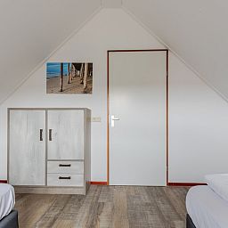 Schlafzimmer im Bungalow T6B Comfort in De Koog, Texel, mit Holzboden und heller Einrichtung, ideal fuer einen erholsamen Aufenthalt auf den Watteninseln.