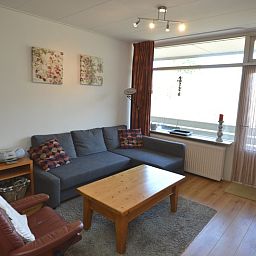 Lichte woonkamer in Appartement Kerckeland 50, De Koog, Texel met ruime bank en decoratieve elementen.