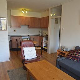 Open keuken en zitgedeelte in Appartement Kerckeland 50, De Koog, Texel met houten meubels en gezellige sfeer.