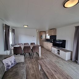 Modern furnished living room of Chaletpark Bregkoog - Chalet 240 De Texelse Berg, De Koog, Texel with open kitchen.