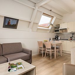 Gezellige woonkamer van C Appartement Comfort 4 in De Koog, Texel, met moderne keuken en eetruimte, ideaal voor een ontspannen verblijf.