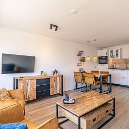 Eetkamer en keuken in Appartement Anna 220, De Koog, Texel met houten eettafel en stijlvolle verlichting.